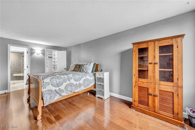 bedroom with ensuite bathroom and light hardwood / wood-style flooring