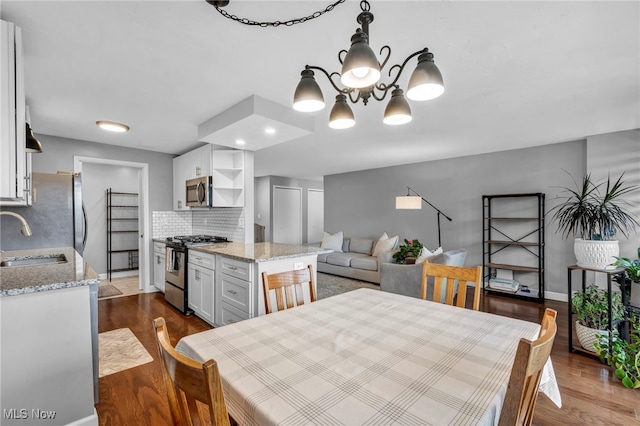 dining area with a notable chandelier, dark wood-type flooring, and sink