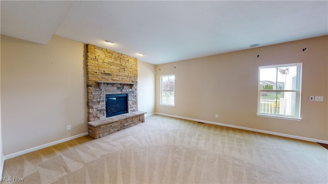 unfurnished living room featuring a stone fireplace and light carpet