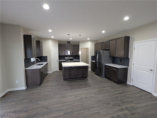 kitchen featuring appliances with stainless steel finishes, backsplash, dark wood-type flooring, decorative light fixtures, and a center island