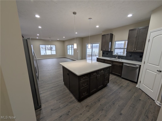 kitchen with dark wood-type flooring, sink, decorative backsplash, appliances with stainless steel finishes, and a kitchen island