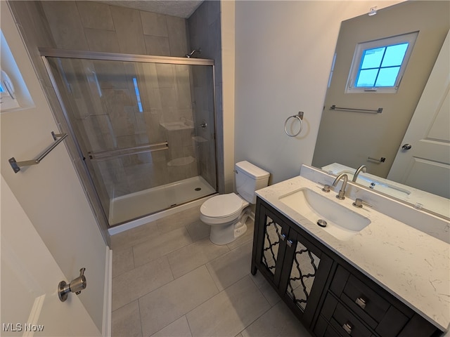 bathroom with tile patterned floors, vanity, an enclosed shower, and toilet