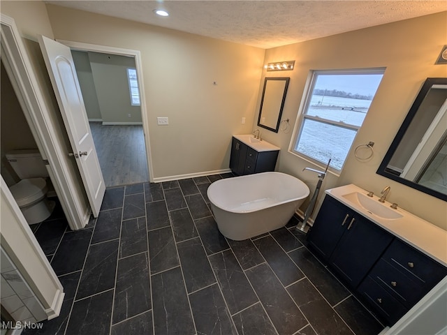 bathroom with a bathtub, vanity, a textured ceiling, wood-type flooring, and toilet