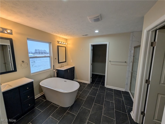 bathroom with a textured ceiling, vanity, and shower with separate bathtub