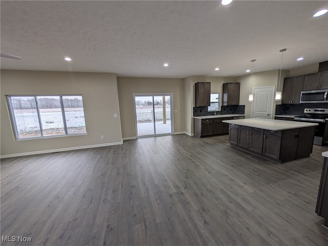 kitchen featuring stainless steel appliances, a kitchen island, plenty of natural light, and dark wood-type flooring