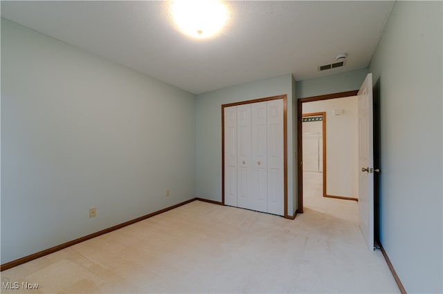 unfurnished bedroom featuring light carpet, baseboards, visible vents, and a closet