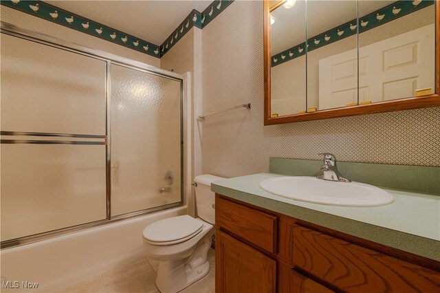 full bath featuring tile patterned flooring, shower / bath combination with glass door, vanity, and toilet