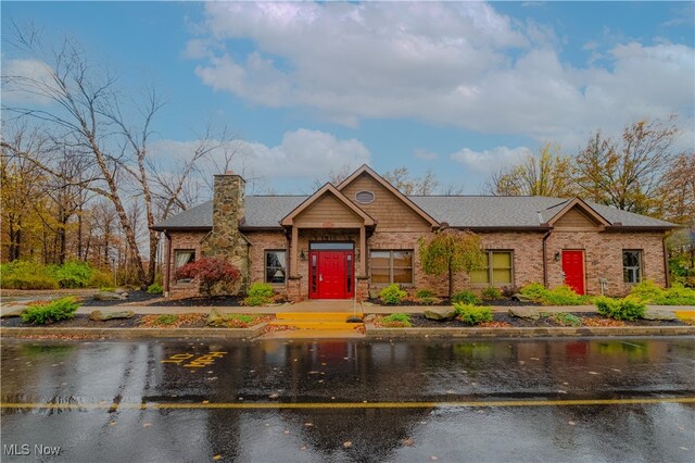 view of front of property with a water view, a chimney, and uncovered parking