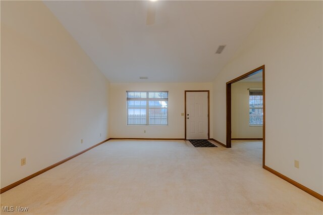 spare room featuring light carpet, a wealth of natural light, and baseboards