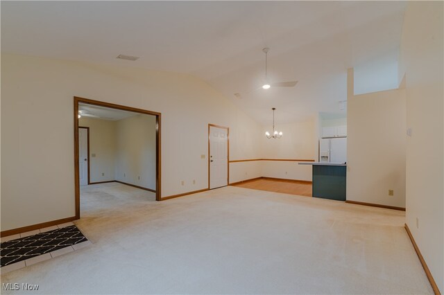 empty room featuring vaulted ceiling, ceiling fan with notable chandelier, baseboards, and light colored carpet