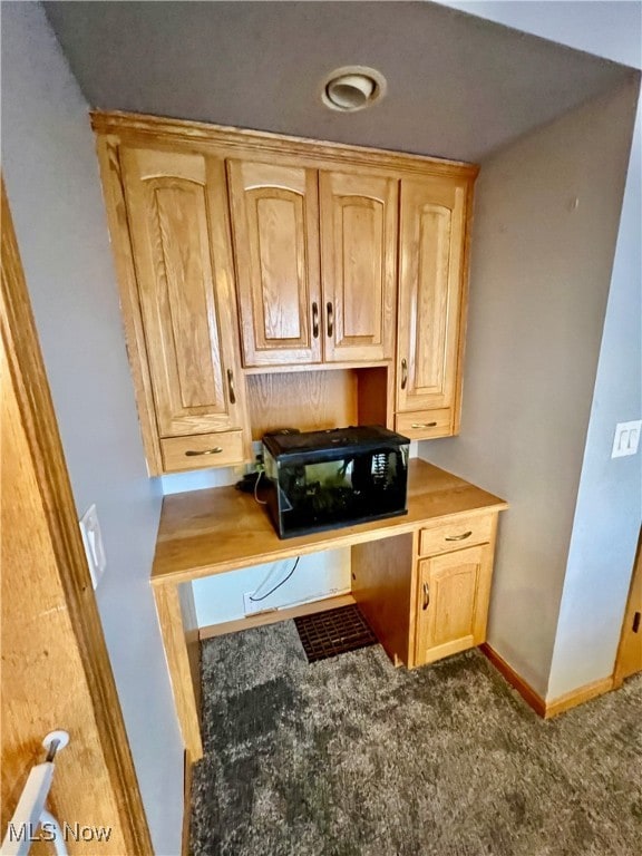 kitchen featuring dark colored carpet and light brown cabinets