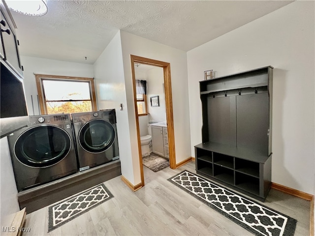 laundry area featuring washer and clothes dryer, light hardwood / wood-style floors, and a textured ceiling