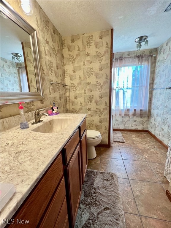 bathroom with tile patterned floors, vanity, a textured ceiling, and toilet