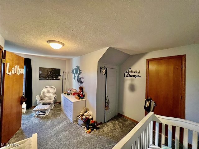 interior space with a nursery area, a textured ceiling, and dark colored carpet