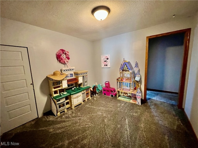 playroom featuring dark colored carpet and a textured ceiling