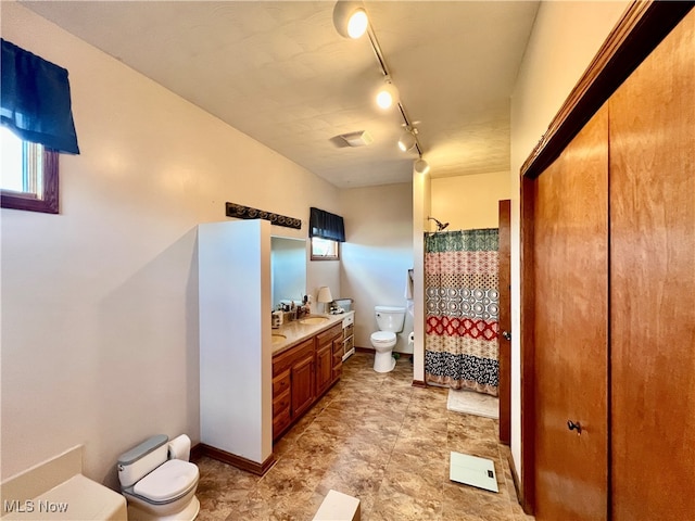 bathroom featuring a shower with curtain, vanity, track lighting, and toilet