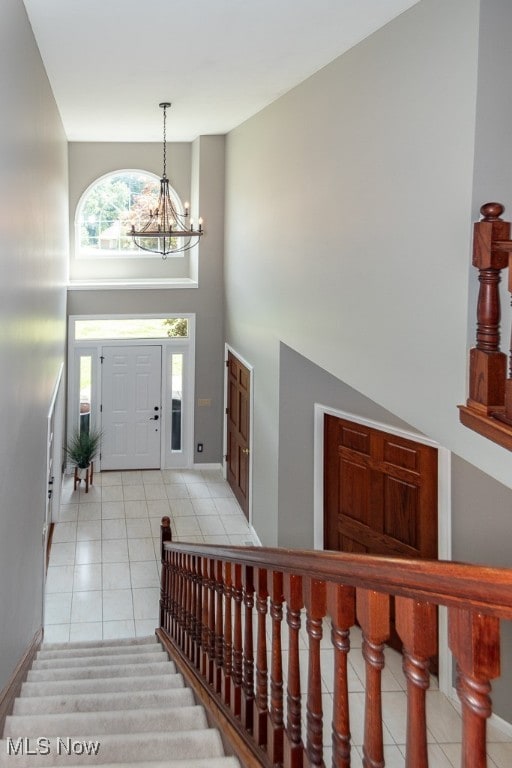 tiled entrance foyer featuring a high ceiling and a chandelier