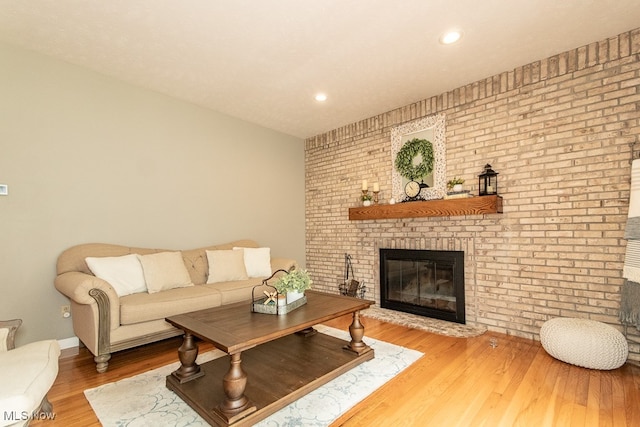 living room with hardwood / wood-style floors, brick wall, and a brick fireplace