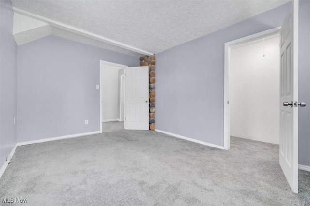 interior space with attic access, baseboards, a textured ceiling, and carpet flooring