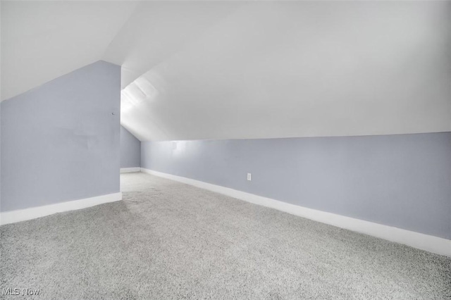 additional living space featuring carpet, baseboards, and vaulted ceiling