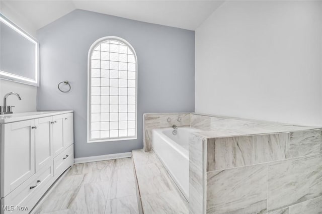 bathroom featuring vaulted ceiling, marble finish floor, a bath, and a healthy amount of sunlight