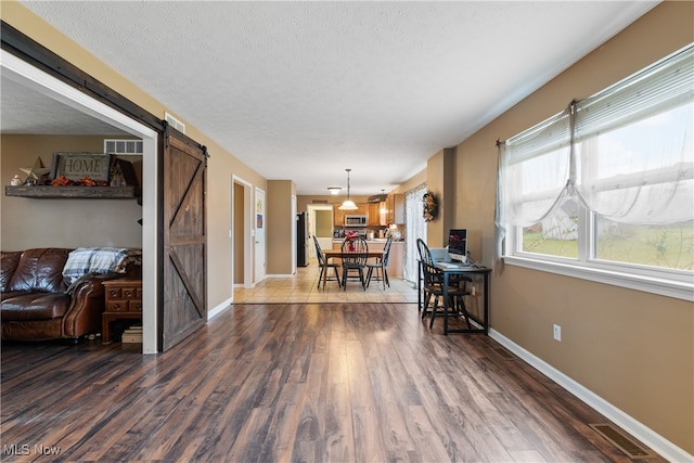 interior space with dark hardwood / wood-style floors, a barn door, and a textured ceiling