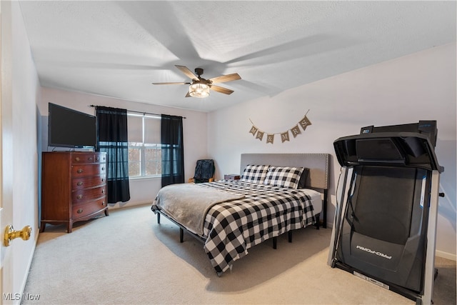 carpeted bedroom featuring ceiling fan and a textured ceiling