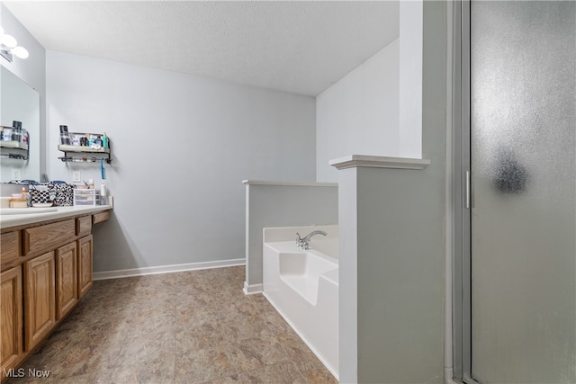 bathroom with a textured ceiling, vanity, and independent shower and bath