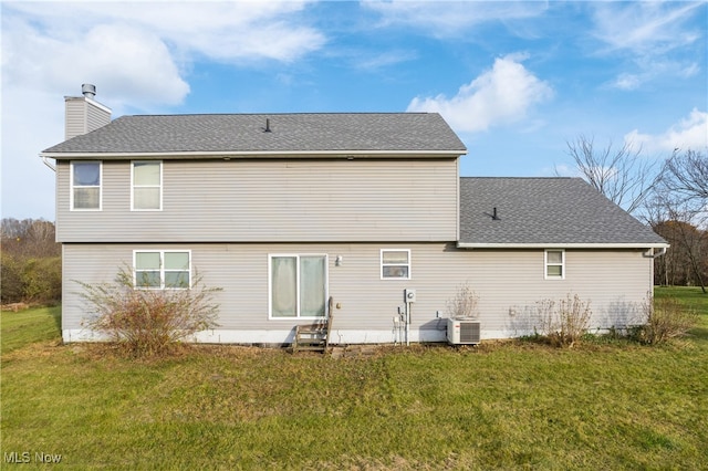 rear view of property featuring a lawn and central AC unit