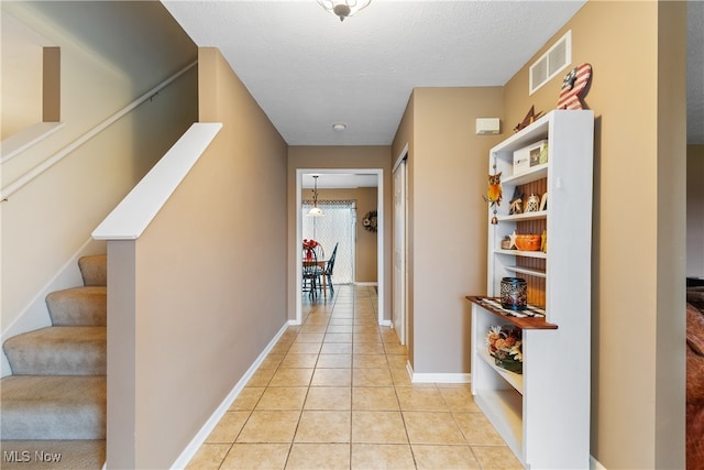 hallway featuring a textured ceiling and light tile patterned flooring