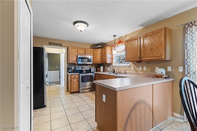 kitchen featuring kitchen peninsula, appliances with stainless steel finishes, sink, pendant lighting, and light tile patterned flooring