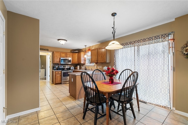 dining area featuring a textured ceiling, light tile patterned floors, and sink