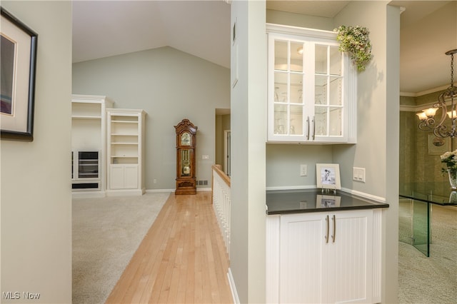 interior space with white cabinets, light hardwood / wood-style floors, lofted ceiling, and pendant lighting