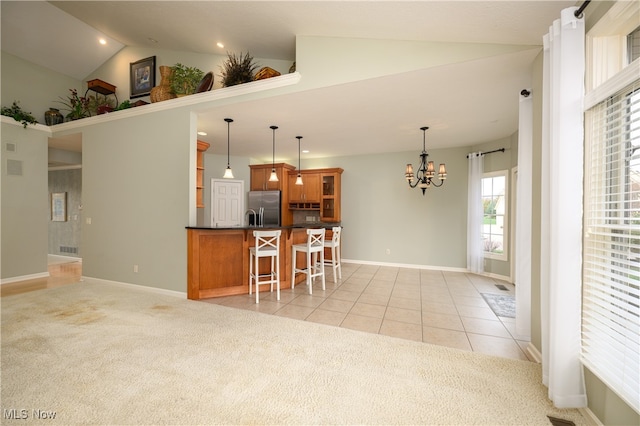 kitchen with pendant lighting, stainless steel refrigerator with ice dispenser, a breakfast bar area, and light carpet