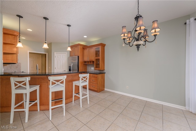 kitchen with a kitchen bar, stainless steel fridge with ice dispenser, decorative light fixtures, and a notable chandelier