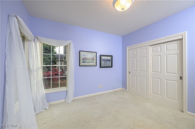 unfurnished bedroom with a textured ceiling, light carpet, and a closet