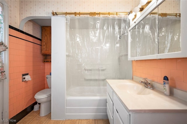 full bathroom with vanity, toilet, tile walls, and shower / bath combo with shower curtain