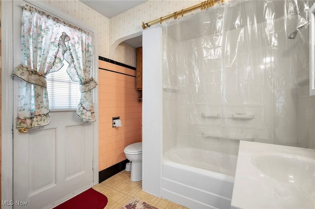 bathroom featuring shower / bath combination with curtain, tile walls, and toilet