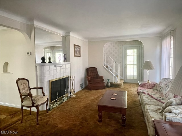 living room with carpet, crown molding, and a tile fireplace