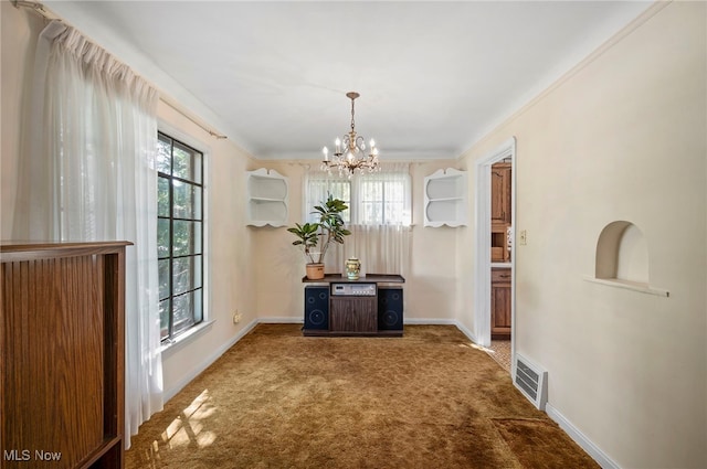 unfurnished dining area with a chandelier, carpet flooring, a wealth of natural light, and crown molding