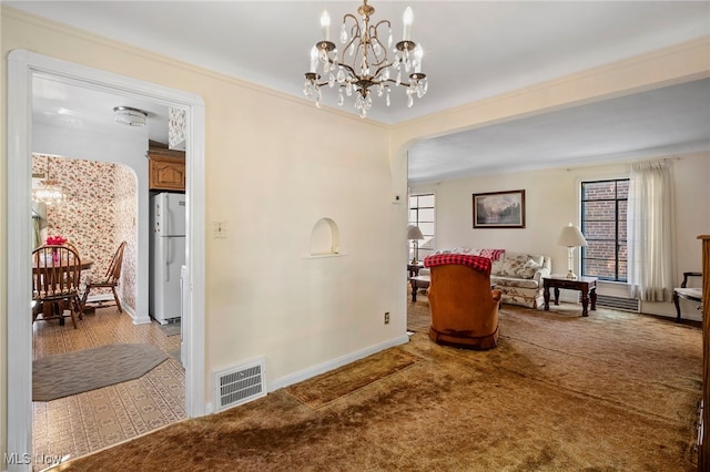 living area featuring crown molding, carpet, and an inviting chandelier