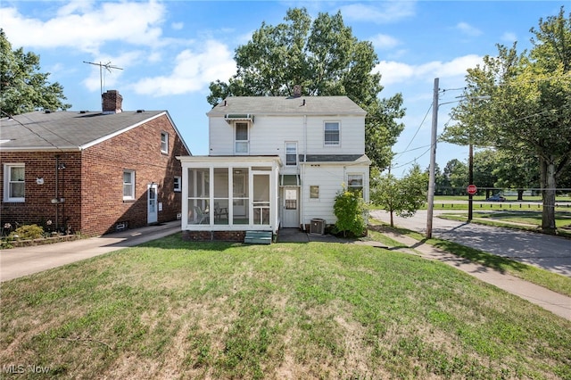 back of property with a sunroom, central AC unit, and a yard