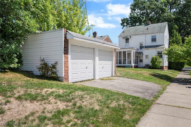 view of front facade with a sunroom, a front yard, central AC unit, a garage, and an outdoor structure