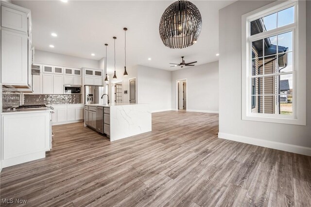 6120 Century Blvd, Canfield, OH 44406 - kitchen featuring stainless steel appliances, open floor plan, decorative backsplash, light wood-type flooring, and baseboards