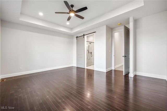 6120 Century Blvd, Canfield, OH 44406 - unfurnished bedroom featuring a barn door, a tray ceiling, baseboards, dark wood-style flooring, and recessed lighting