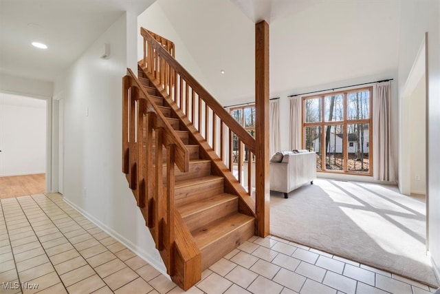 staircase featuring a towering ceiling and carpet