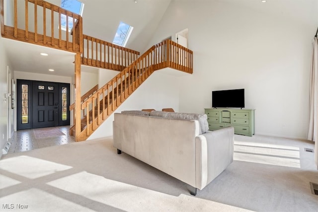 carpeted living room with high vaulted ceiling and a skylight