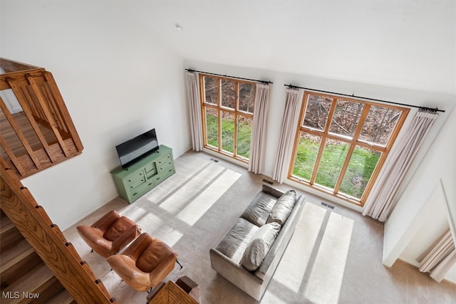 carpeted living room with a towering ceiling