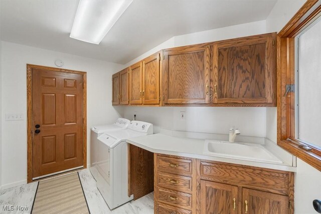 laundry area with washing machine and dryer, sink, cabinets, and light hardwood / wood-style flooring