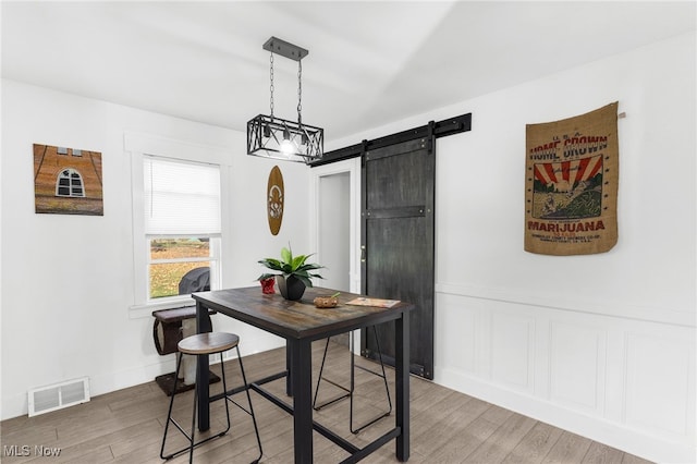 dining area featuring a barn door and hardwood / wood-style flooring